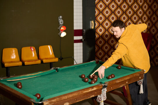 Male rehearsing pool shot in vintage bar setting