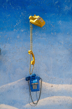 Yellow and blue vintage telephones on a textured, painted blue wall. Ouarzazate, Morocco