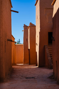 Narrow alley with traditional earthen buildings and clear blue sky in the background Ouarzazate, Morocco