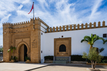 Historic building with ornamental architecture and a flag under a blue sky with clouds. Rabat, Morocco