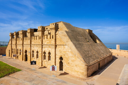 Historic stone fortress with crenellated walls under a bright blue sky near the sea. Rabat, Morocco
