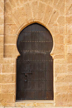 Rustic wooden door with medieval design set in a stone archway. Rabat, Morocco
