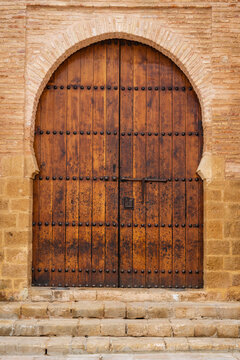 Rustic wooden door with iron studs in stone historical building facade. Rabat, Morocco