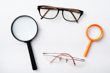 Frame made from various vision-enhancing tools&mdash;glasses and magnifying lenses&mdash;top view, white background.