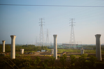A construction site with large concrete pillars and power lines under a clear blue sky. Chengdu, Sichuan, China