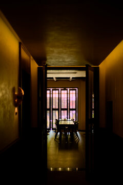 Dimly lit hallway leading to a warmly illuminated dining area with a table and chairs. Trip from Guilin to Chengdu, Guangxi, Sichuan, China