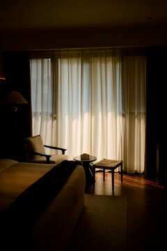 Sunlight filters through sheer curtains illuminating a cozy room with a chair and table. Trip from Guilin to Chengdu, Guangxi, Sichuan, China