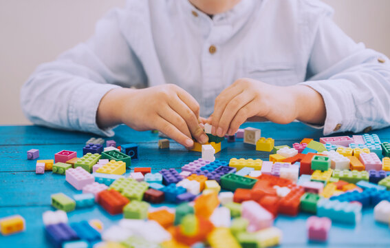 Child playing and building with colorful toy bricks, plastic blocks.