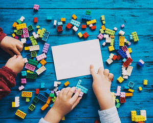 Fototapeta premium Child hands playing with colored toy bricks.