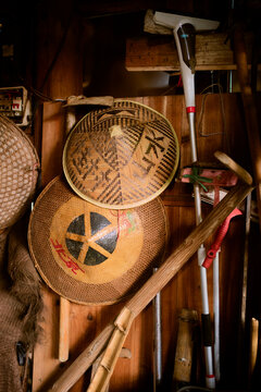 Traditional woven hats and gardening tools arranged against a wooden wall background. Trip from Guilin to Chengdu, Guangxi, Sichuan, China