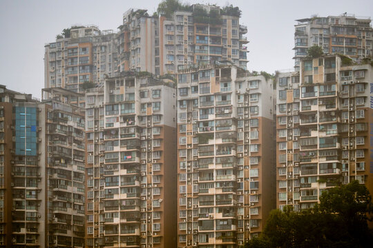 High-rise residential apartment buildings with lush rooftops and misty sky in urban setting. Trip from Guilin to Chengdu, Guangxi, Sichuan, China