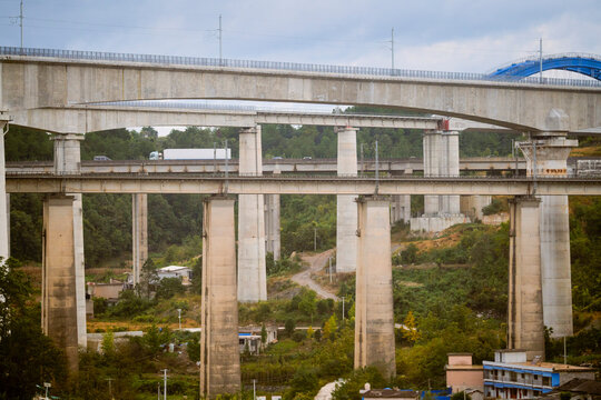 Multiple layers of elevated highways with vehicles and surrounding greenery under cloudy skies. Trip from Guilin to Chengdu, Guangxi, Sichuan, China