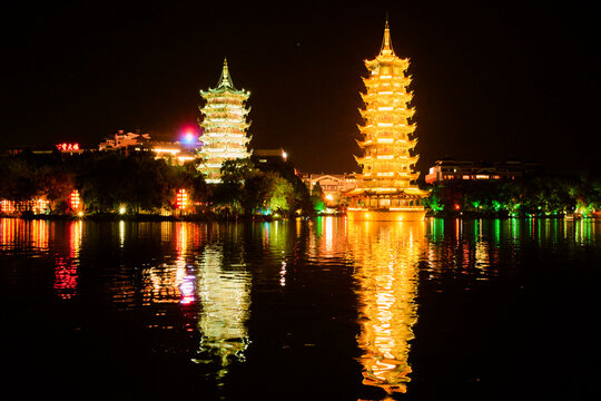 Illuminated pagodas reflecting in a lake at night against a dark sky. Trip from Guilin to Chengdu, Guangxi, Sichuan, China