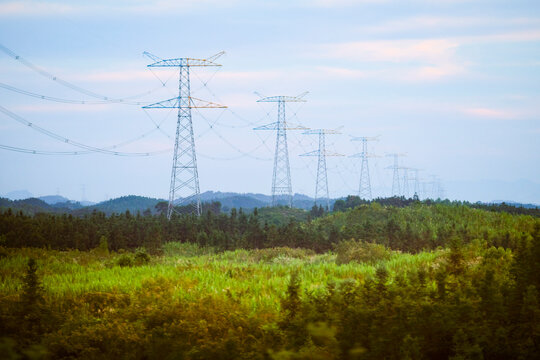 Tall power lines stretch across lush green fields under a blue sky.  Trip from Guilin to Chengdu, Guangxi, Sichuan, China