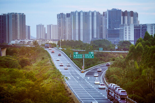 A cityscape with high-rise buildings and a highway filled with vehicles surrounded by greenery. Trip from Guilin to Chengdu, Guangxi, Sichuan, China