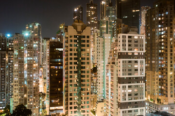 Skyscrapers lit at night in a bustling city with numerous windows illuminating the scene. Hongkong, China