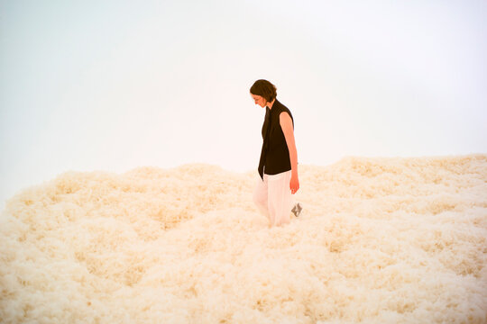 Person in black top and white pants walking on fluffy white surface against soft white background. Hongkong, China