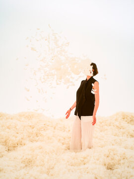 Person stands amidst a swirling cloud of feathers on a feather-covered floor.  Hongkong, China
