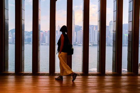 Silhouette of a person walking in a modern building with a cityscape view of skyscrapers. Hongkong, China