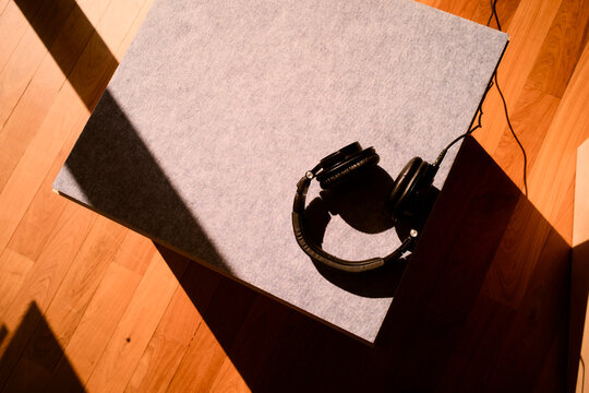 Headphones resting on a table in warm sunlight with wooden floor and shadow play. Hongkong, China