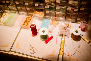 Craft workspace with colorful threads, beads, scissors, and organized storage boxes on a table. Shanghai, China