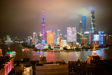 Shanghai skyline illuminated at night with colorful lights and a cloudy sky. Shanghai, China