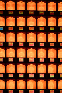 Rows of illuminated orange lanterns with intricate designs and text in square alcoves. Shanghai, China