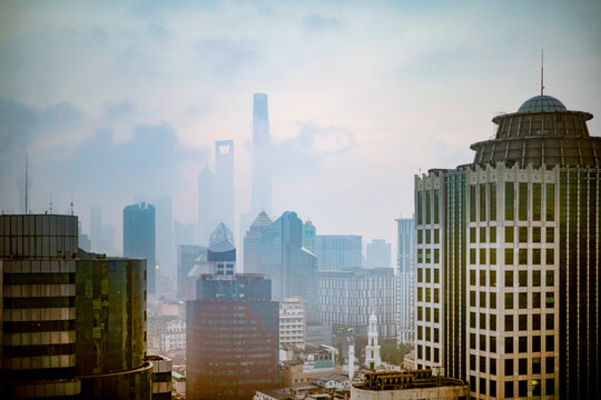 A city skyline with tall skyscrapers seen through a haze in the early morning light. Shanghai, China