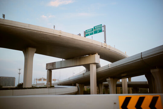 Elevated highways intersect against a clear blue sky, featuring overpass signage. Shanghai, China