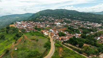 Aerial view of a lush green landscape with a small town nestled between rolling hills and winding roads. Barichara, Colombia