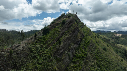 A lush, green mountain peak under a sky filled with dramatic clouds. Colombia