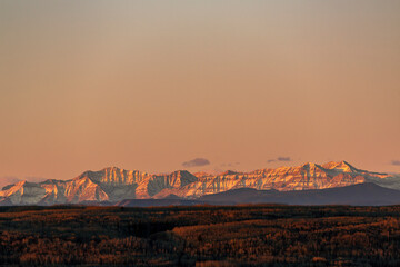 Majestic mountain range at sunset with warm tones and a clear sky in the background. West of Calgary, Canada
