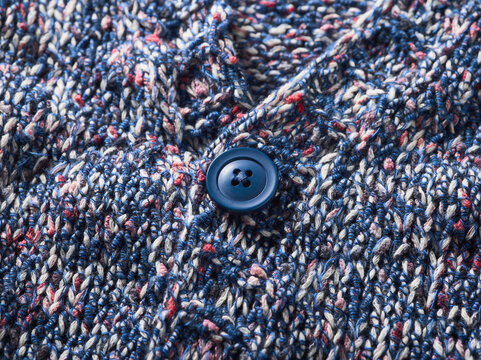 Close-up of a blue button on a multicolored textured knitted fabric.