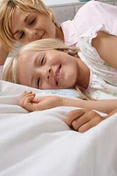Mother and daughter snuggling happily in bed, enjoying a relaxing morning together. Germany