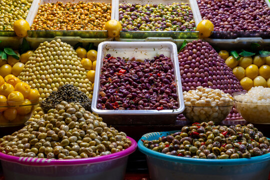 Vibrant display of assorted olives and pickles in colorful baskets at a market stall. Fez, Morocco