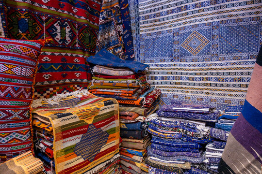 Vibrant stacks of colorful woven rugs with intricate patterns in a market display. Fez, Morocco