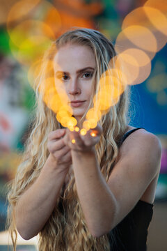Woman with long blonde hair holds vibrant fairy lights in an artistic display. WA, USA