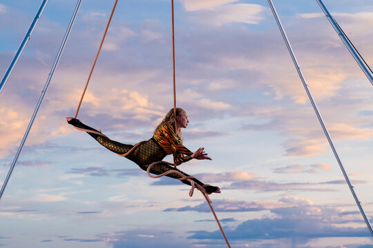 Aerial performer gracefully balances in a split pose against a vibrant sunset sky. WA, USA
