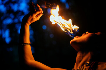 Fire performer exhaling flames from a torch against a dark, dramatic background. WA, USA