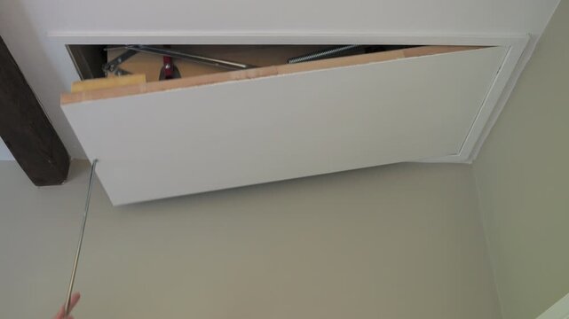 4K: Opening a Loft or Attic Hatch with a metal rod towards the ceiling. Stock Video Clip Footage.