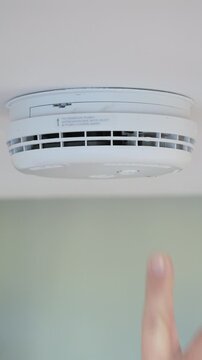 4K: Testing a smoke alarm in a house. A man uses his finger to push the button. Vertical.  Stock Video Clip Footage.
