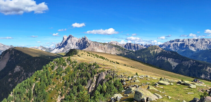 Mountain landscape panorama from Resciesa Dedora towards Mount seceda and Mount Pic against a blue summer background.