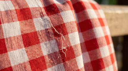 Macro close up texture of traditional Thai red and white checkered Pha Khao Ma loincloth fabric with sunlight and loose threads details