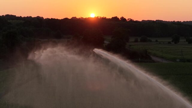 Aerial of a Sprinkler machine in front of the sunset, Corn monoculture in a hot summer.