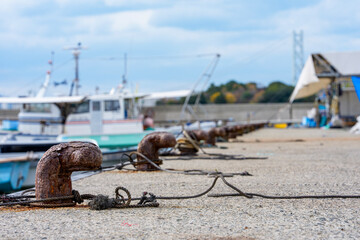 港に並ぶ錆びた係船柱と停泊中の漁船