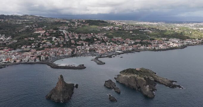 Aerial view of the dramatic coast of Aci Trezza, with its dark rocks jutting out of the sea contrasting with the white buildings, Aci Trezza, Sicily, Italy.