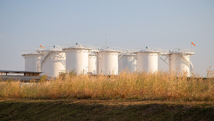 Group of storage fuel crude oil tanks in petroleum industrial refinery area against blue clear sky background, low angle view with copy space