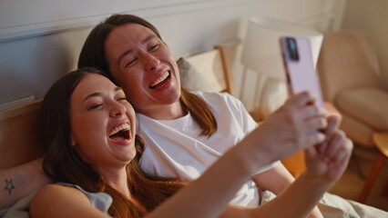 Funny couple creating pictures using smartphone together bed apartment closeup