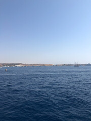 Expansive blue ocean waters under a clear sky with a distant coastal city skyline