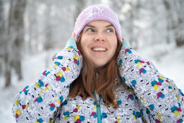 Beautiful happy girl are smiling outdoors in the snowy winter, closeup portrait.